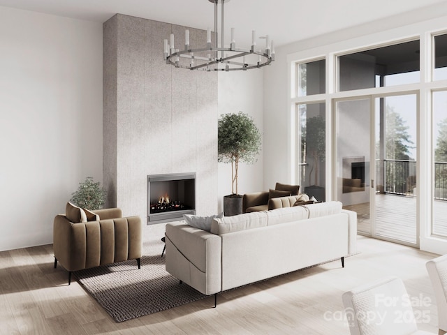 living area featuring a lit fireplace, a chandelier, and light wood-type flooring