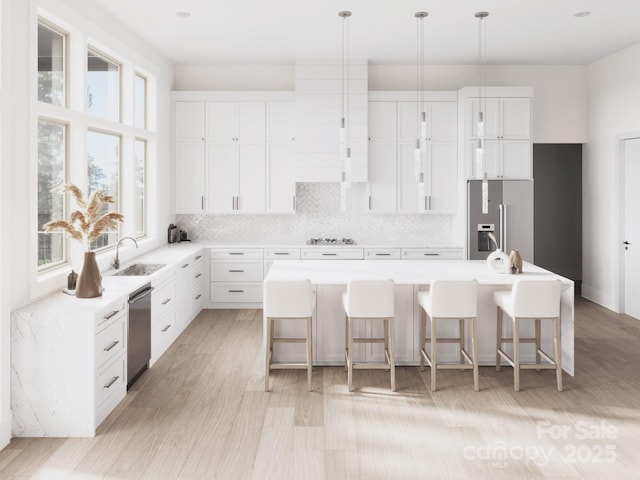 kitchen featuring stainless steel appliances, tasteful backsplash, a breakfast bar area, a sink, and a center island