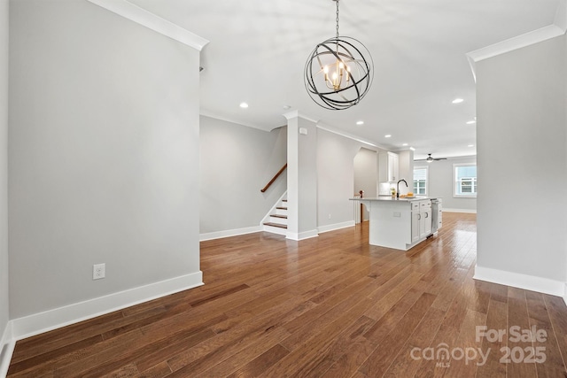 1162 E 36th St, Charlotte, NC 28205 - unfurnished living room featuring crown molding, wood finished floors, stairs, baseboards, and a chandelier