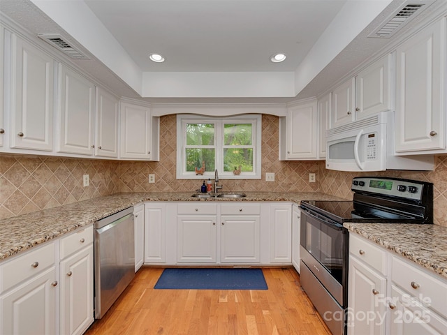4025 Woodfox Dr, Charlotte, NC 28277 - kitchen featuring stainless steel appliances, a sink, light wood finished floors, white cabinetry, and tasteful backsplash