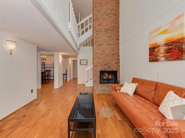 4025 Woodfox Dr, Charlotte, NC 28277 - living area featuring light wood finished floors, a fireplace, a high ceiling, stairway, and wood walls