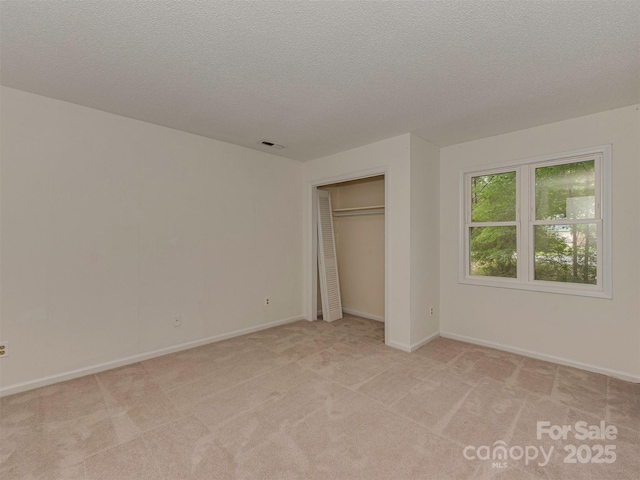 4025 Woodfox Dr, Charlotte, NC 28277 - unfurnished bedroom featuring a textured ceiling, light colored carpet, baseboards, and a closet