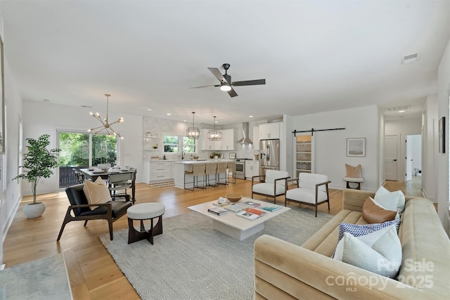 3163 Maury St, Charlotte, NC 28208 - living room featuring a barn door, a ceiling fan, light wood finished floors, and a chandelier