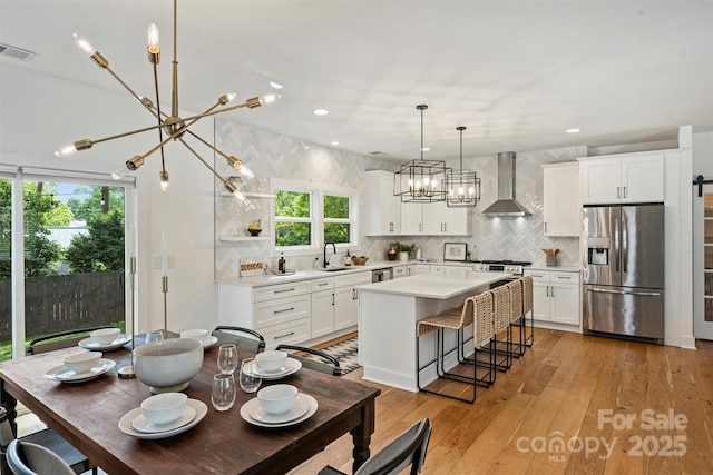 3163 Maury St, Charlotte, NC 28208 - kitchen with stainless steel fridge, wall chimney range hood, a chandelier, a sink, and healthy amount of natural light
