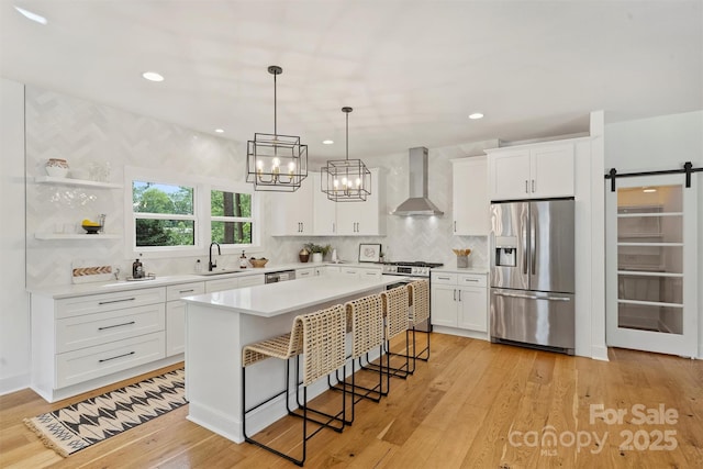 3163 Maury St, Charlotte, NC 28208 - kitchen featuring stainless steel appliances, wall chimney range hood, a sink, light countertops, and a breakfast bar