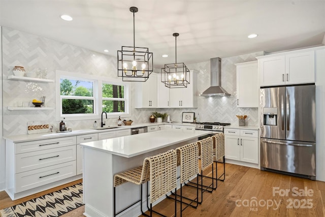 3163 Maury St, Charlotte, NC 28208 - kitchen with stainless steel appliances, wall chimney range hood, a sink, light countertops, and decorative backsplash