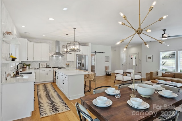 3163 Maury St, Charlotte, NC 28208 - kitchen featuring appliances with stainless steel finishes, a sink, wall chimney exhaust hood, tasteful backsplash, and light wood finished floors
