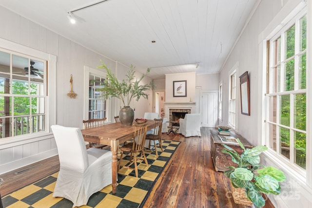 dining area featuring hardwood / wood-style floors, rail lighting, a brick fireplace, and wooden ceiling