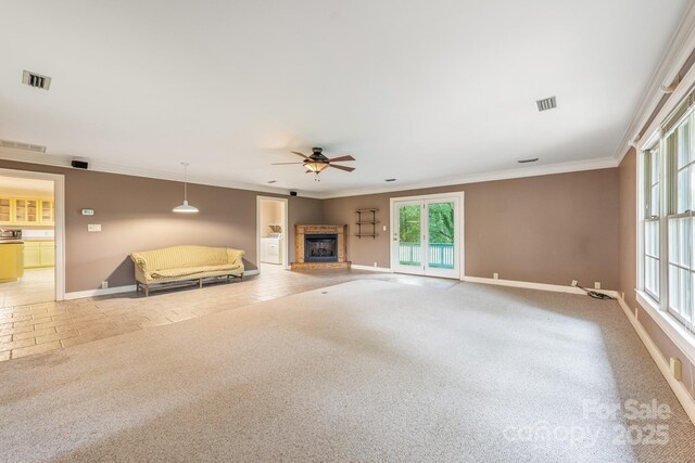 unfurnished living room with ceiling fan, baseboards, a fireplace with raised hearth, crown molding, and plenty of natural light