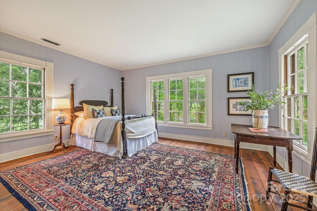 bedroom with multiple windows, hardwood / wood-style floors, and ornamental molding