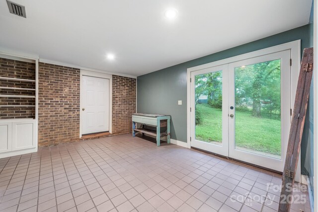 unfurnished living room featuring brick wall, tile patterned flooring, french doors, and recessed lighting