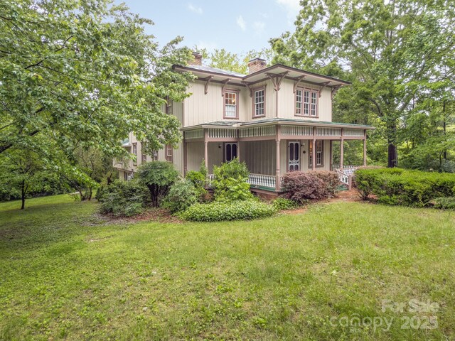 italianate home featuring a chimney, a front lawn, and covered porch