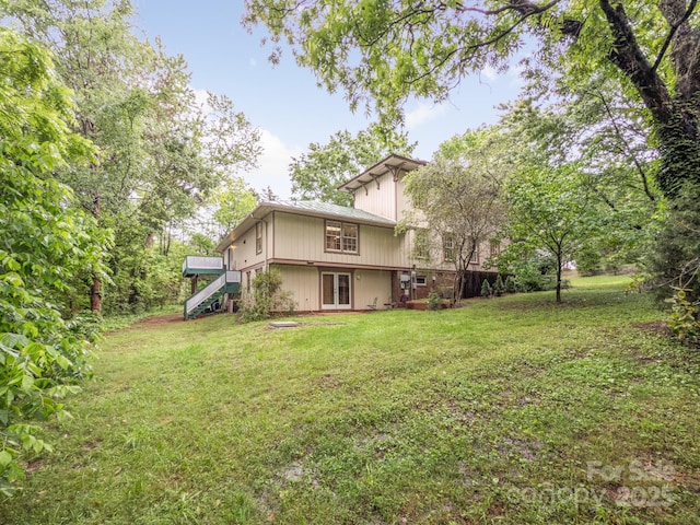 back of property featuring stairs and a yard