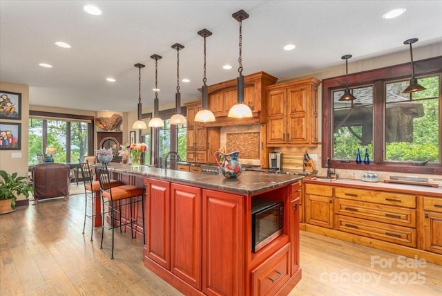 2461 Eagles Nest Rd, Waynesville, NC 28786 - kitchen featuring light wood-style floors, recessed lighting, a kitchen bar, decorative backsplash, and dark countertops