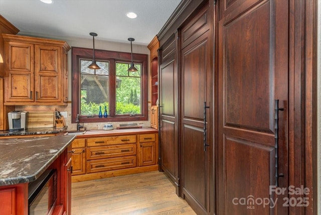 2461 Eagles Nest Rd, Waynesville, NC 28786 - kitchen with black microwave, hanging light fixtures, recessed lighting, light wood-style flooring, and dark stone countertops