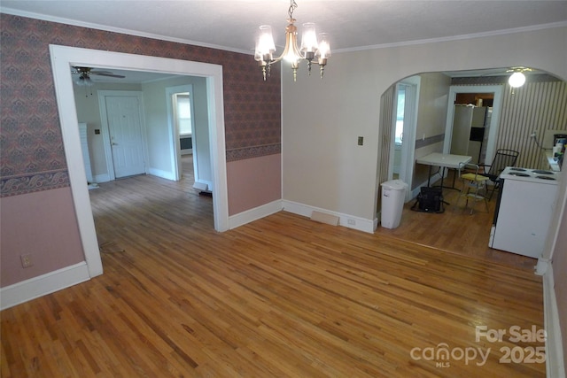 unfurnished dining area featuring arched walkways, baseboards, wood finished floors, wallpapered walls, and a chandelier