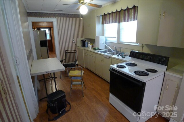 kitchen featuring electric range oven, white fridge with ice dispenser, a sink, light wood-style flooring, and light countertops