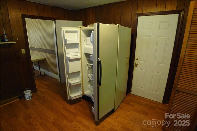 kitchen with wood finished floors, freestanding refrigerator, and wooden walls