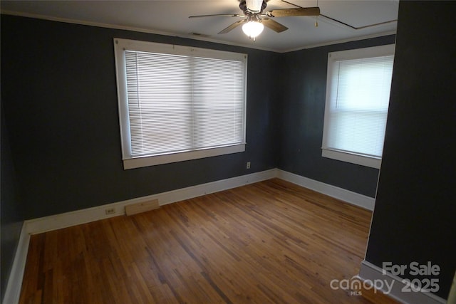 empty room featuring plenty of natural light, a ceiling fan, ornamental molding, wood finished floors, and baseboards
