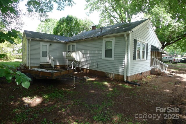 back of property with entry steps, crawl space, and a chimney