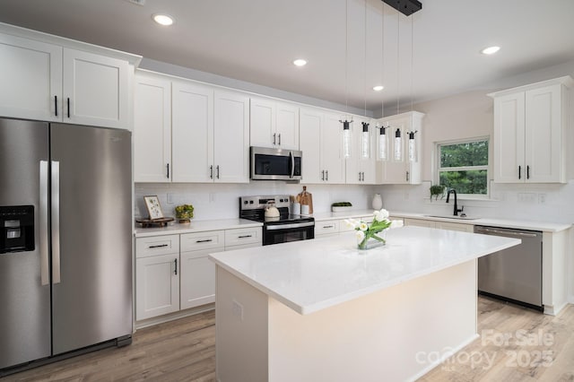 207 9th Ct NE, Conover, NC 28613 - kitchen featuring appliances with stainless steel finishes, a sink, light wood finished floors, decorative backsplash, and white cabinetry