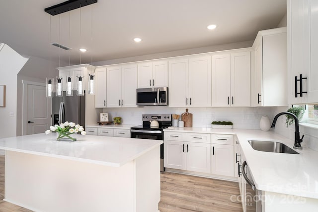 207 9th Ct NE, Conover, NC 28613 - kitchen featuring appliances with stainless steel finishes, a sink, light wood-type flooring, a kitchen island, and recessed lighting
