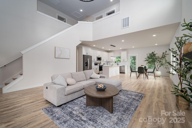 207 9th Ct NE, Conover, NC 28613 - living room with stairway, light wood-style flooring, a towering ceiling, baseboards, and recessed lighting