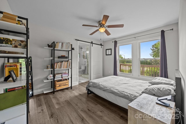 5371 Davidson Rd, Davidson, NC 28036 - bedroom featuring a barn door, wood finished floors, connected bathroom, a ceiling fan, and baseboards