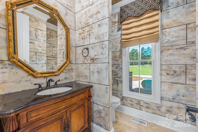 bathroom featuring toilet, vanity, and baseboards