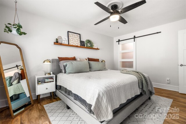 3900 Langley Rd, Charlotte, NC 28215 - bedroom featuring a barn door, wood finished floors, a ceiling fan, and baseboards