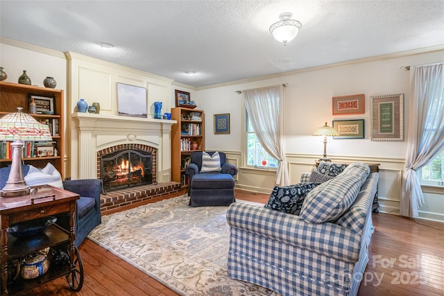 287 Anne St, Rutherfordton, NC 28139 - living area featuring wood-type flooring, a textured ceiling, a brick fireplace, crown molding, and a wainscoted wall