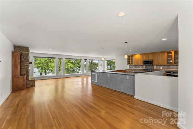 2218 Mallard Cove Dr, Nebo, NC 28761 - kitchen with stainless steel microwave, open floor plan, glass insert cabinets, light wood-style flooring, and backsplash