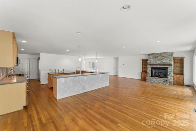 2218 Mallard Cove Dr, Nebo, NC 28761 - kitchen featuring a sink, a center island with sink, light wood-style flooring, recessed lighting, and a stone fireplace