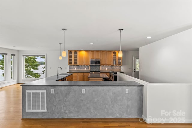 2218 Mallard Cove Dr, Nebo, NC 28761 - kitchen featuring stainless steel microwave, a sink, brown cabinets, a spacious island, and light wood-style flooring