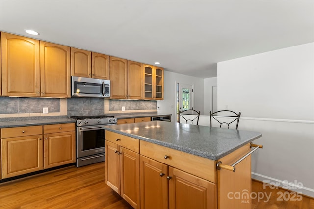 2218 Mallard Cove Dr, Nebo, NC 28761 - kitchen featuring stainless steel appliances, wood finished floors, decorative backsplash, a kitchen island, and glass insert cabinets