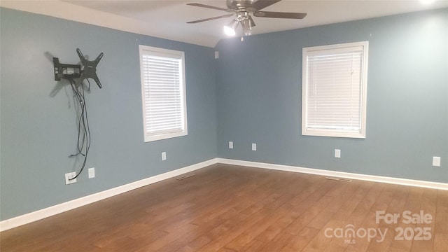 empty room featuring wood finished floors, a ceiling fan, and baseboards