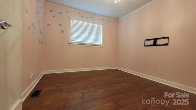 spare room featuring crown molding, dark wood-type flooring, and baseboards