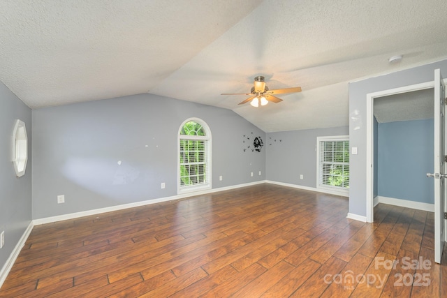 unfurnished living room with ceiling fan, wood finished floors, plenty of natural light, baseboards, and a textured ceiling