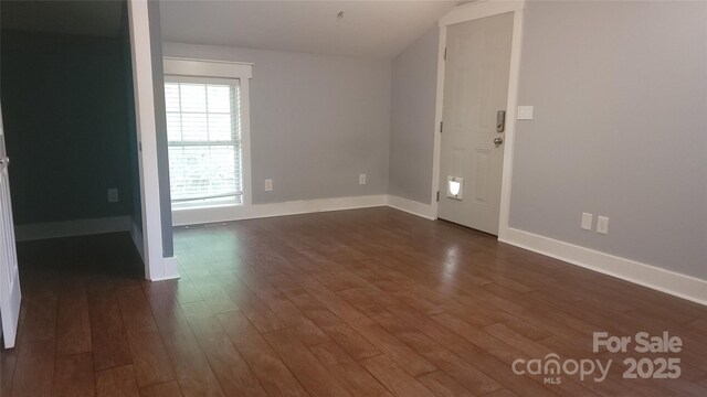 unfurnished room featuring dark wood-type flooring and baseboards