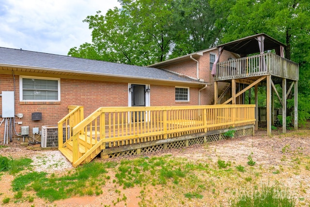 rear view of property with central AC, brick siding, a wooden deck, stairway, and a shingled roof