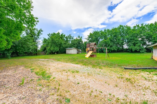 view of yard featuring a playground, a storage unit, an outbuilding, and view of scattered trees
