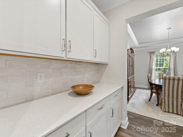 603 Southstone Dr, Matthews, NC 28104 - kitchen with a chandelier, dark wood-style flooring, white cabinetry, backsplash, and light stone countertops