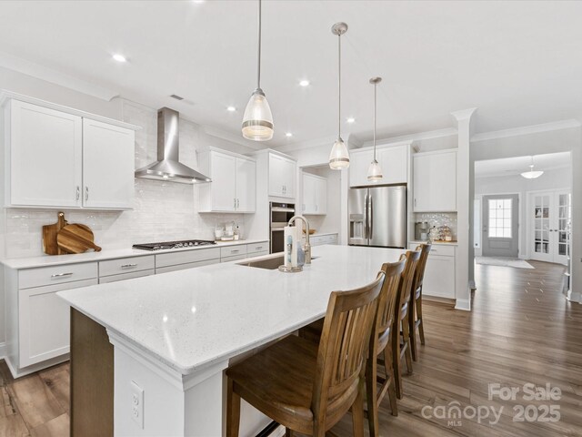 603 Southstone Dr, Matthews, NC 28104 - kitchen with appliances with stainless steel finishes, wall chimney exhaust hood, a sink, a center island with sink, and wood finished floors