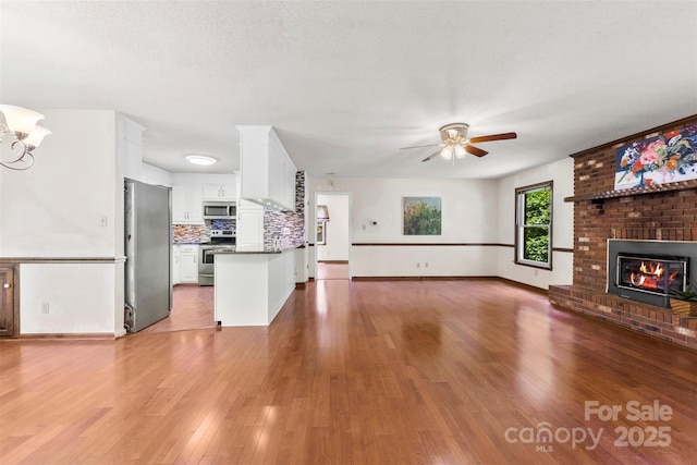 113 Helena St, Mount Holly, NC 28120 - unfurnished living room with wood finished floors, ceiling fan, a fireplace, and baseboards