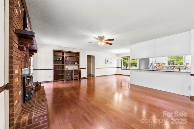 113 Helena St, Mount Holly, NC 28120 - unfurnished living room with a ceiling fan, wood-type flooring, plenty of natural light, and a brick fireplace