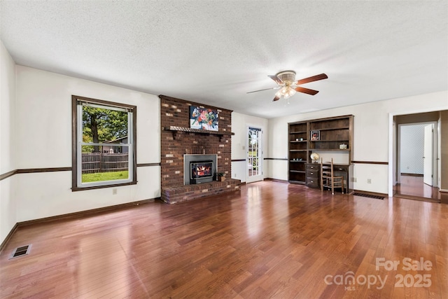 113 Helena St, Mount Holly, NC 28120 - unfurnished living room with healthy amount of natural light, ceiling fan, wood finished floors, a brick fireplace, and a textured ceiling
