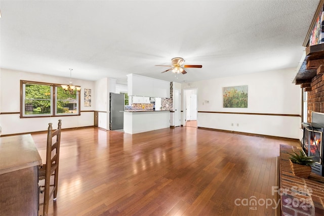 113 Helena St, Mount Holly, NC 28120 - unfurnished living room featuring a brick fireplace, a chandelier, ceiling fan, and hardwood / wood-style flooring