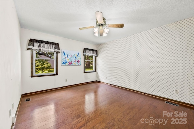 113 Helena St, Mount Holly, NC 28120 - unfurnished room featuring wallpapered walls, baseboards, hardwood / wood-style flooring, an accent wall, and a ceiling fan