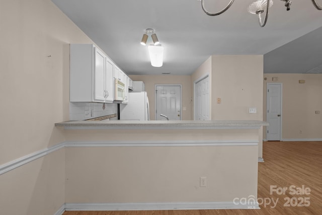 112 Dujon Ct, Mount Holly, NC 28120 - kitchen featuring white appliances, light countertops, light wood-style floors, a peninsula, and baseboards