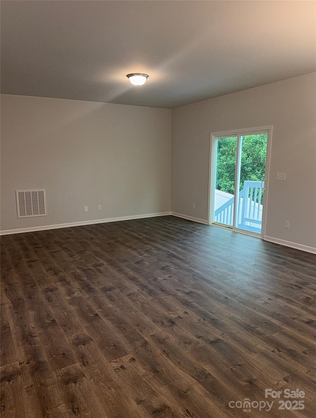 unfurnished room with dark wood-style flooring and baseboards